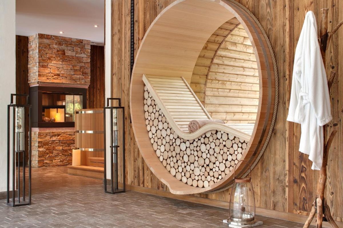 une chaise en bois dans une chambre avec un miroir dans l'établissement LA CHENEAUDIÈRE - Hôtel Spa - Relais & Châteaux - Restaurant étoilé, à Colroy-la-Roche