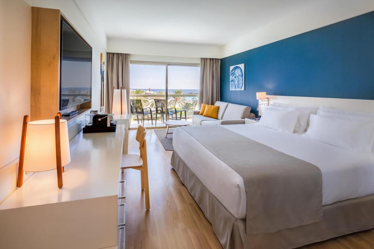Un dormitorio con una cama grande y una sala de estar. en Barceló Fuerteventura Mar, en Caleta de Fuste