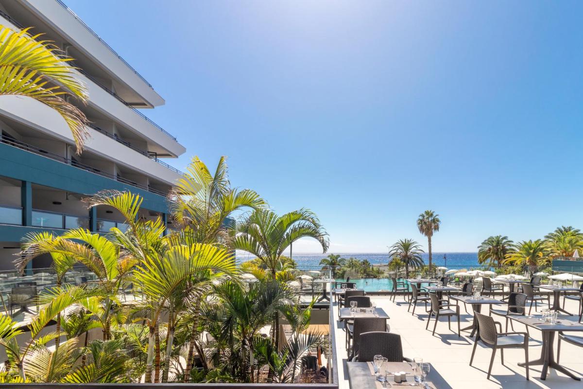 uma vista para um resort com mesas e cadeiras e para o oceano em Enotel Lido - All Inclusive no Funchal