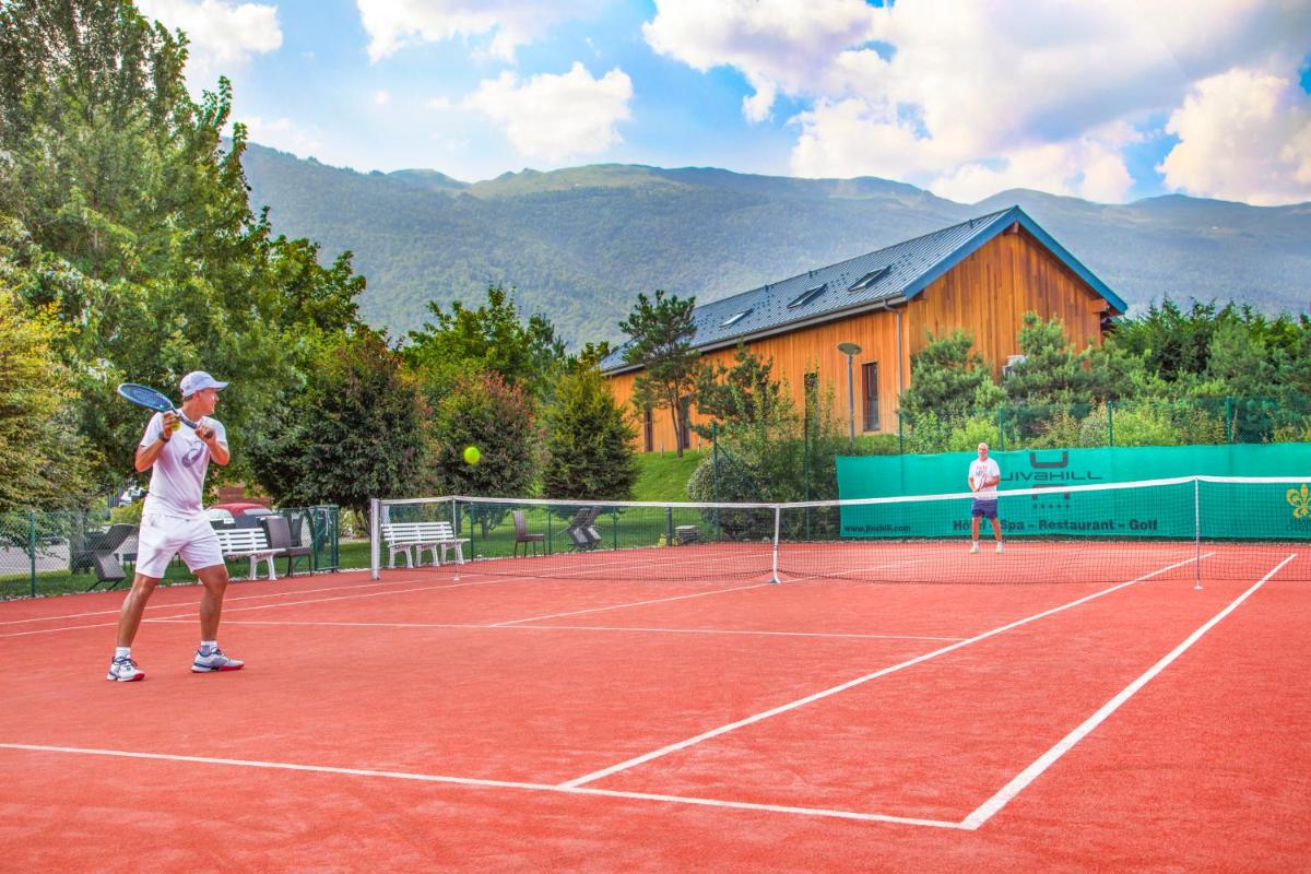 deux personnes jouant au tennis sur un court de tennis dans l'établissement Jiva Hill Resort - Genève, à Crozet