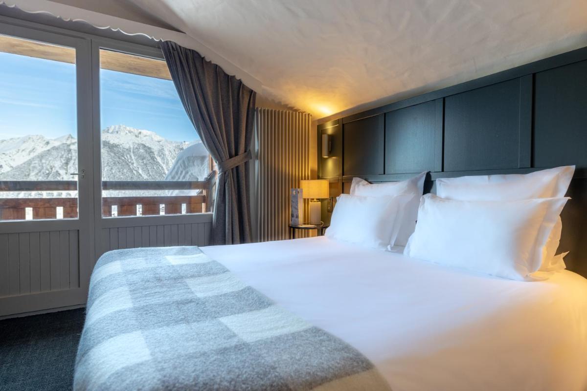 - une chambre avec un lit et une vue sur les montagnes dans l'établissement Grand Hôtel Courchevel 1850, à Courchevel