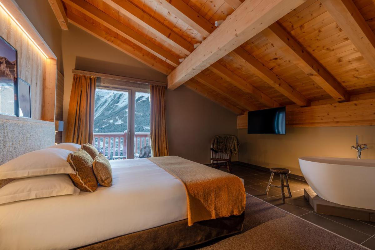 une chambre avec un lit et une baignoire dans une chambre dans l'établissement ILY Hotels & Spa La Rosiere, à La Rosière 57 autres photos
