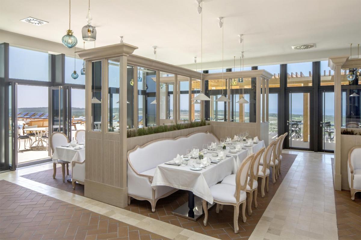 uma sala de jantar com mesa, cadeiras e janelas em Royal Obidos Scenic Resort em Praia del Rei