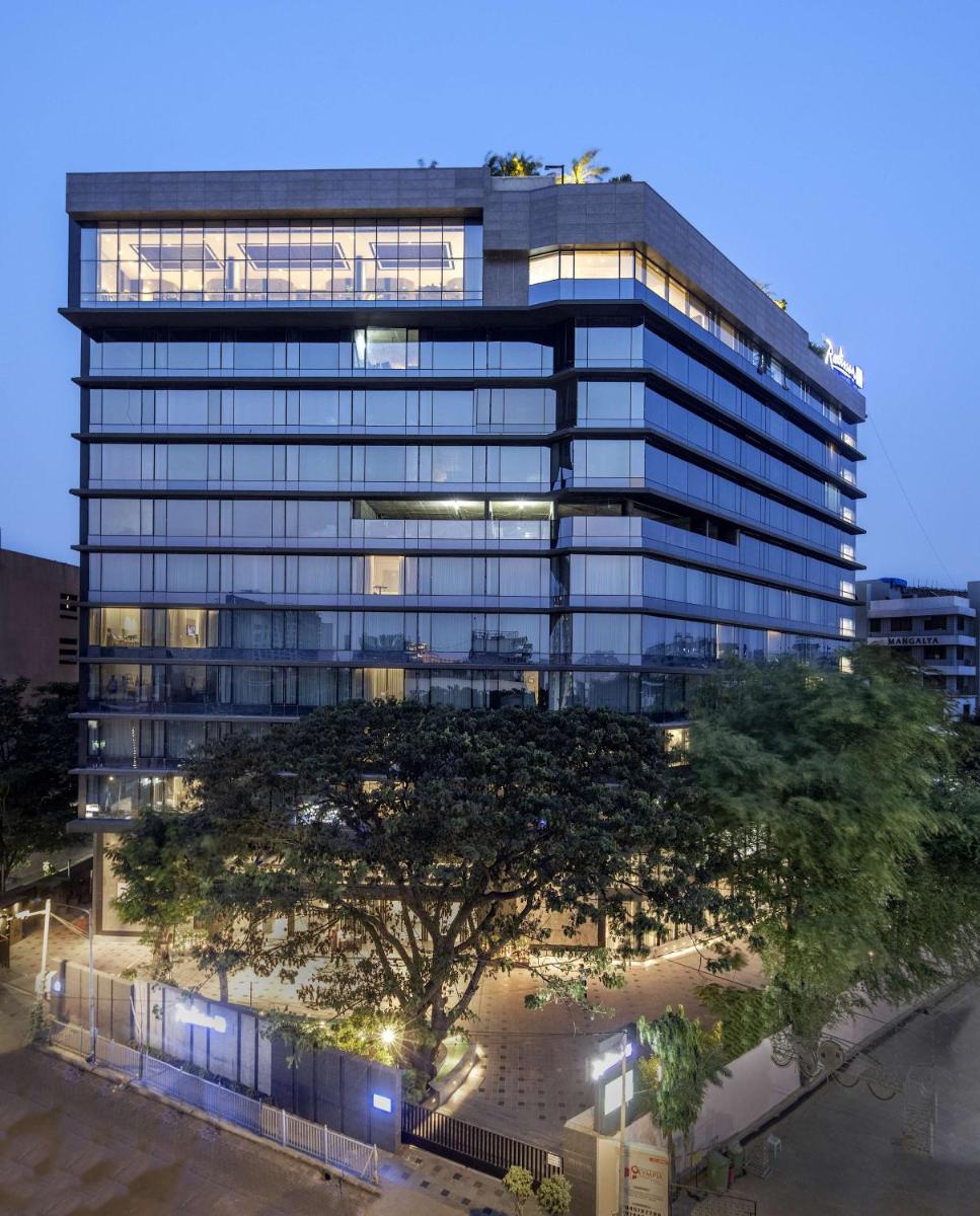 a tall building with a tree in front of it at Radisson Blu Mumbai International Airport in Mumbai a tall building with a tree in front of it at Radisson Blu Mumbai International Airport in Mumbai