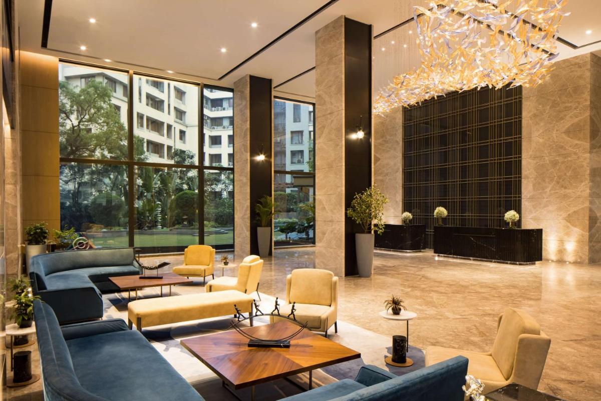 a lobby with couches and tables in a building at Radisson Blu Mumbai International Airport in Mumbai a lobby with couches and tables in a building at Radisson Blu Mumbai International Airport in Mumbai