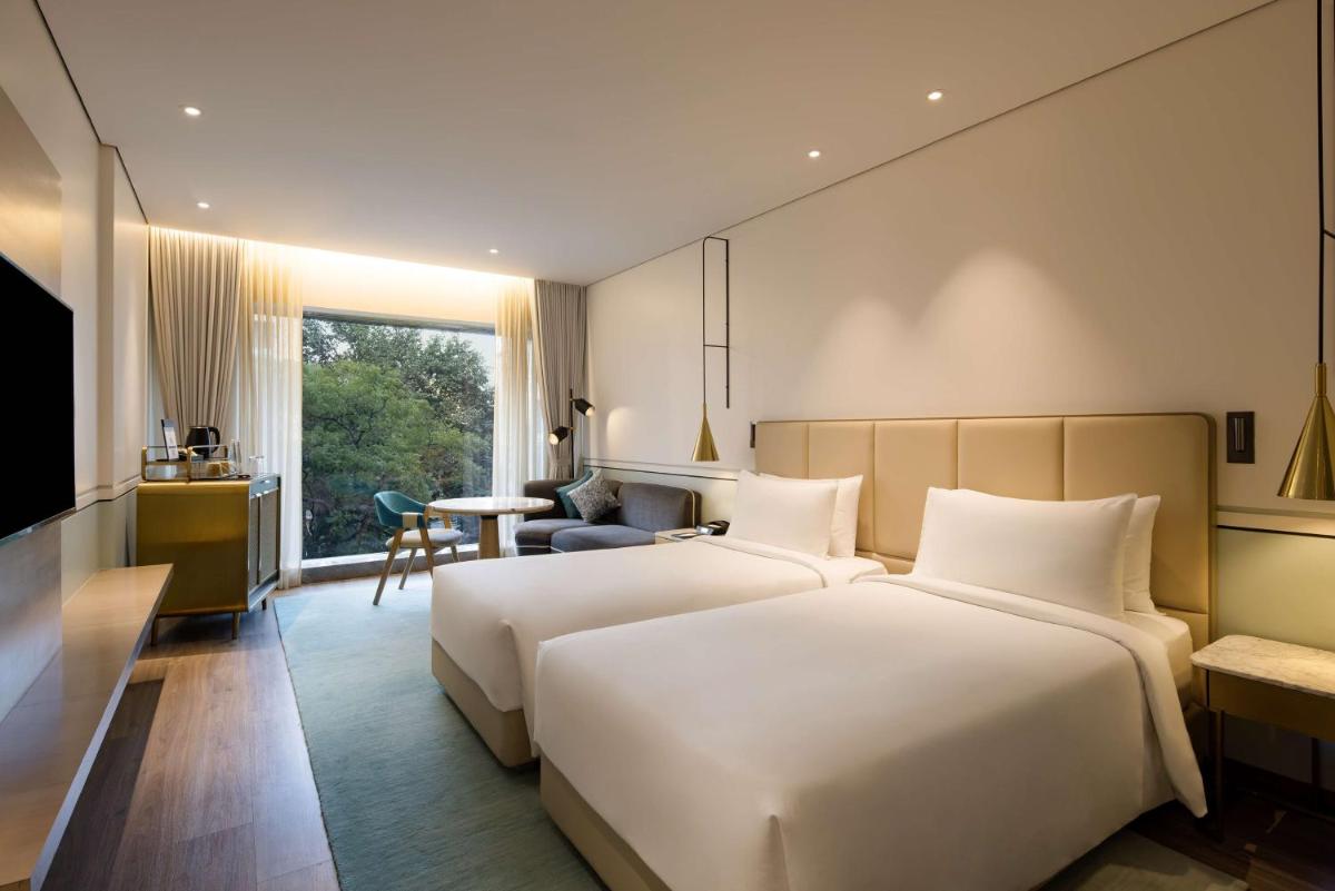 a hotel room with two beds and a table at Radisson Blu Mumbai International Airport in Mumbai a hotel room with two beds and a table at Radisson Blu Mumbai International Airport in Mumbai