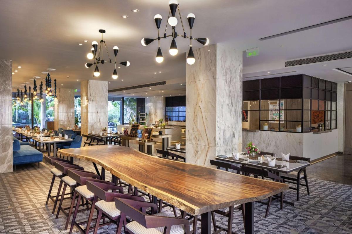 a restaurant with a large wooden table and chairs at Radisson Blu Mumbai International Airport in Mumbai a restaurant with a large wooden table and chairs at Radisson Blu Mumbai International Airport in Mumbai