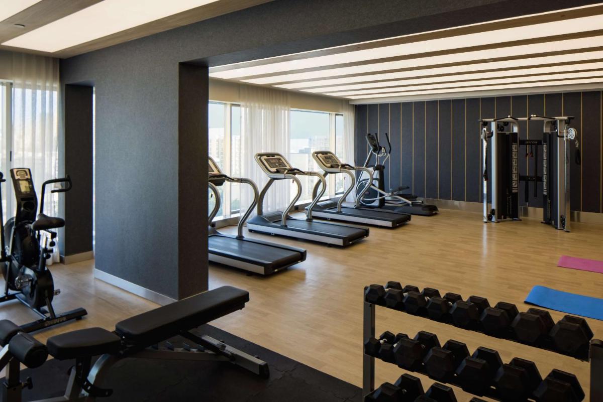 a gym with a row of treadmills and machines at Radisson Blu Mumbai International Airport in Mumbai a gym with a row of treadmills and machines at Radisson Blu Mumbai International Airport in Mumbai
