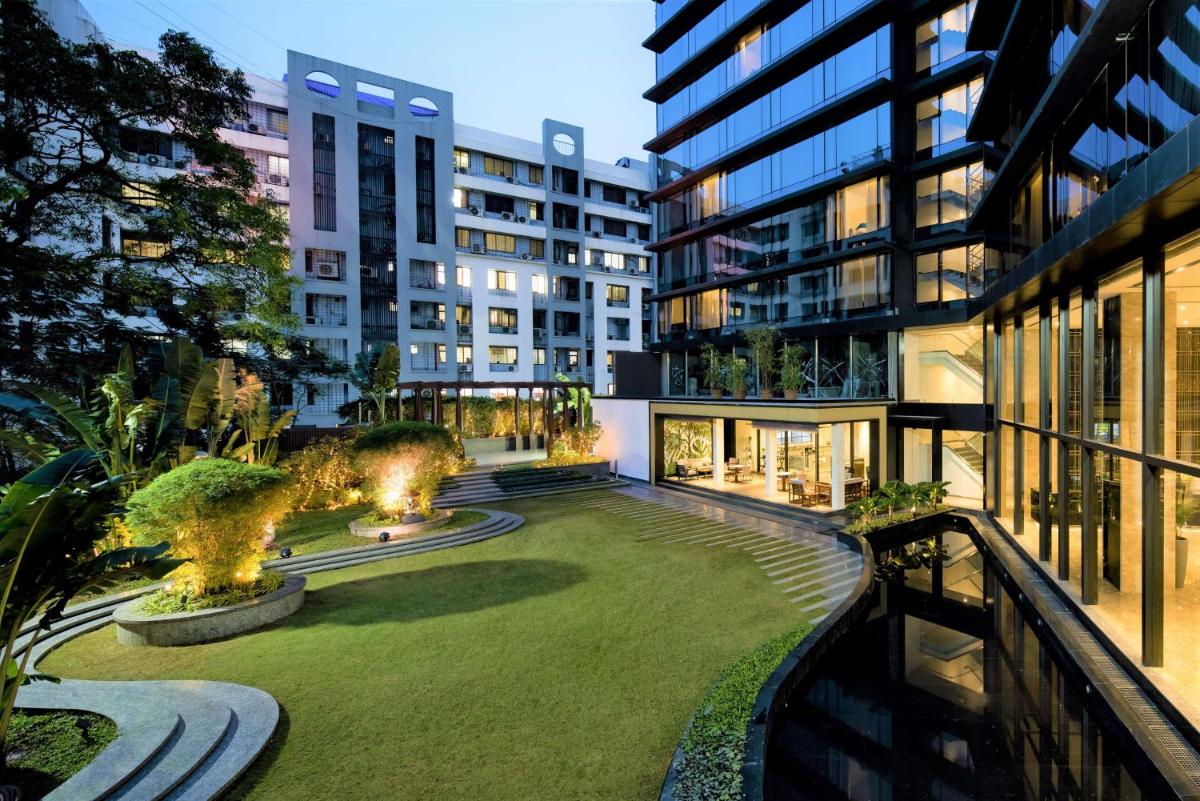 a courtyard in a building with a lawn and buildings at Radisson Blu Mumbai International Airport in Mumbai a courtyard in a building with a lawn and buildings at Radisson Blu Mumbai International Airport in Mumbai