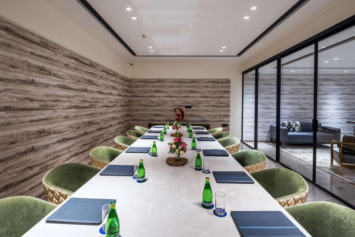 a long conference room with a long table and green chairs at Radisson Blu Mumbai International Airport in Mumbai a long conference room with a long table and green chairs at Radisson Blu Mumbai International Airport in Mumbai