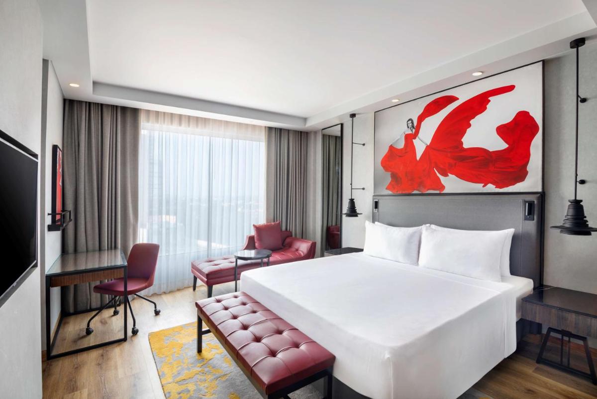 a hotel room with a large white bed and a chair at Radisson RED Chandigarh Mohali in Chandīgarh