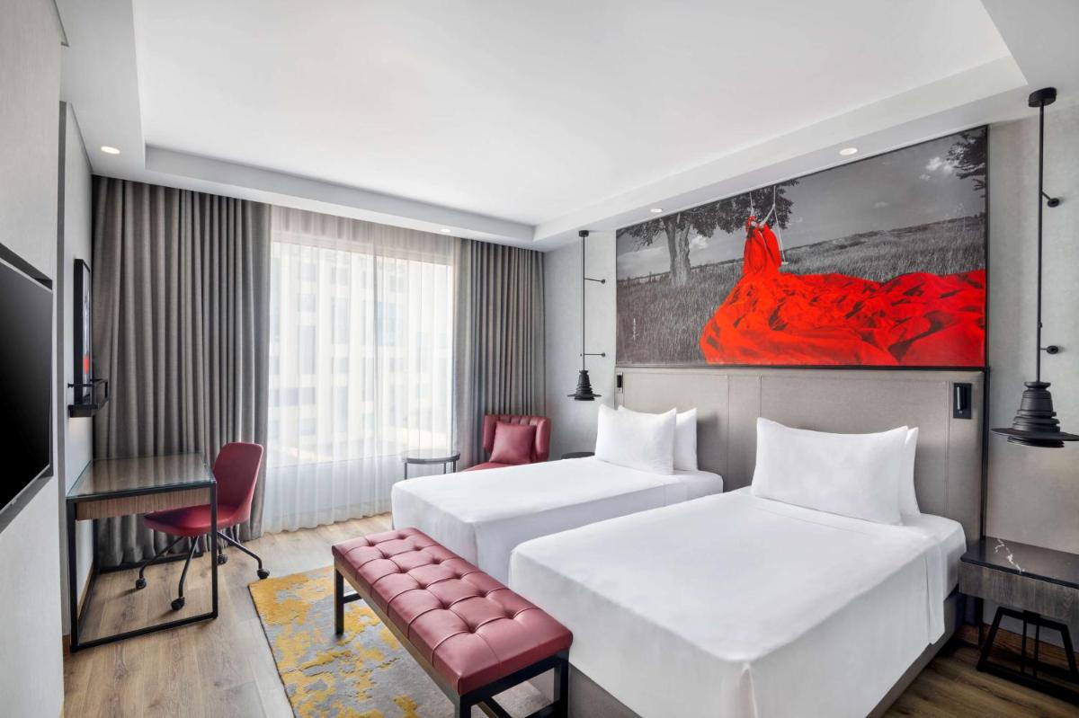 a hotel room with two beds and a red painting at Radisson RED Chandigarh Mohali in Chandīgarh