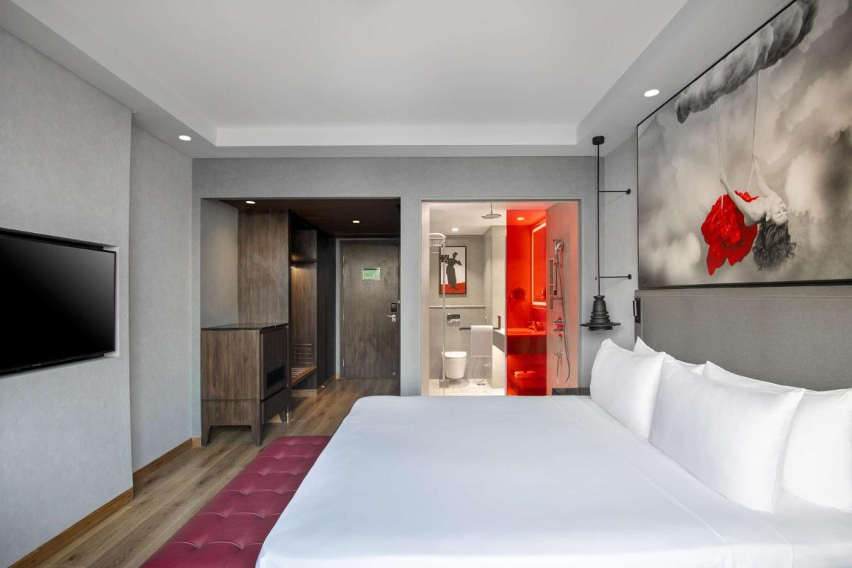 a bedroom with a large white bed and a bathroom at Radisson RED Chandigarh Mohali in Chandīgarh