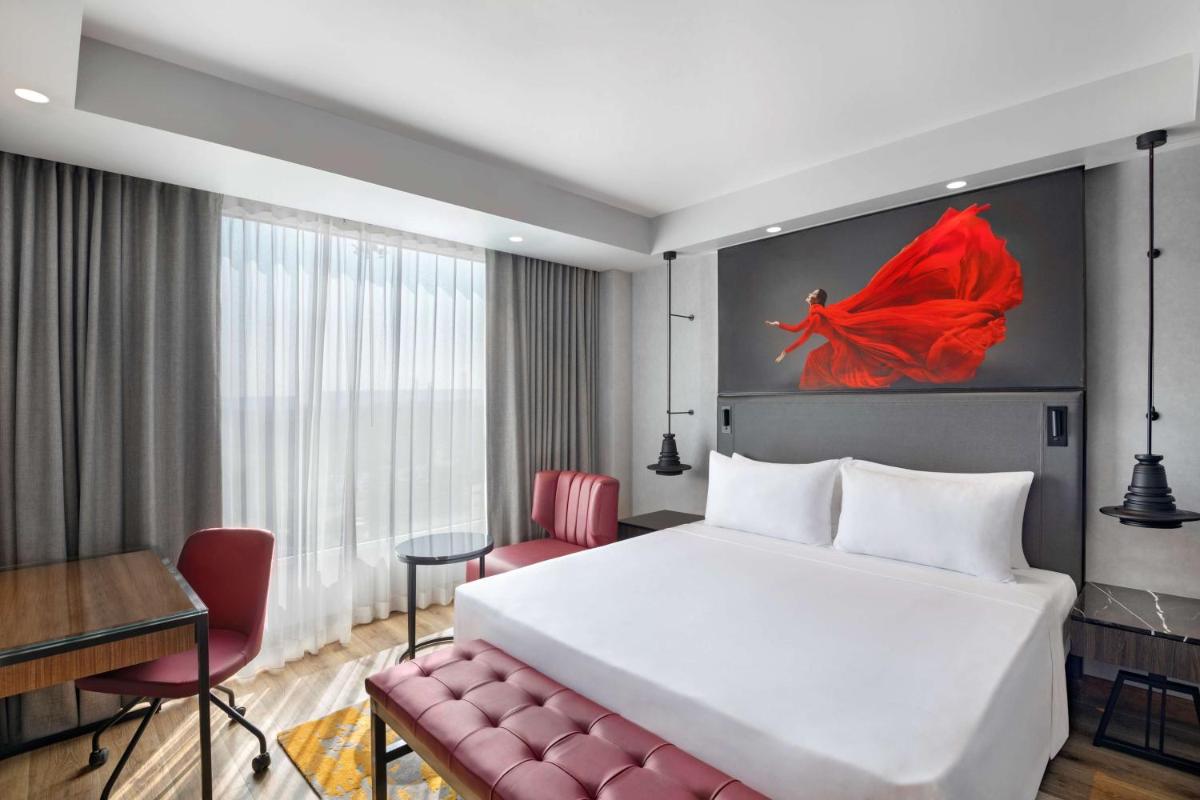 a hotel room with a large bed and a red chair at Radisson RED Chandigarh Mohali in Chandīgarh