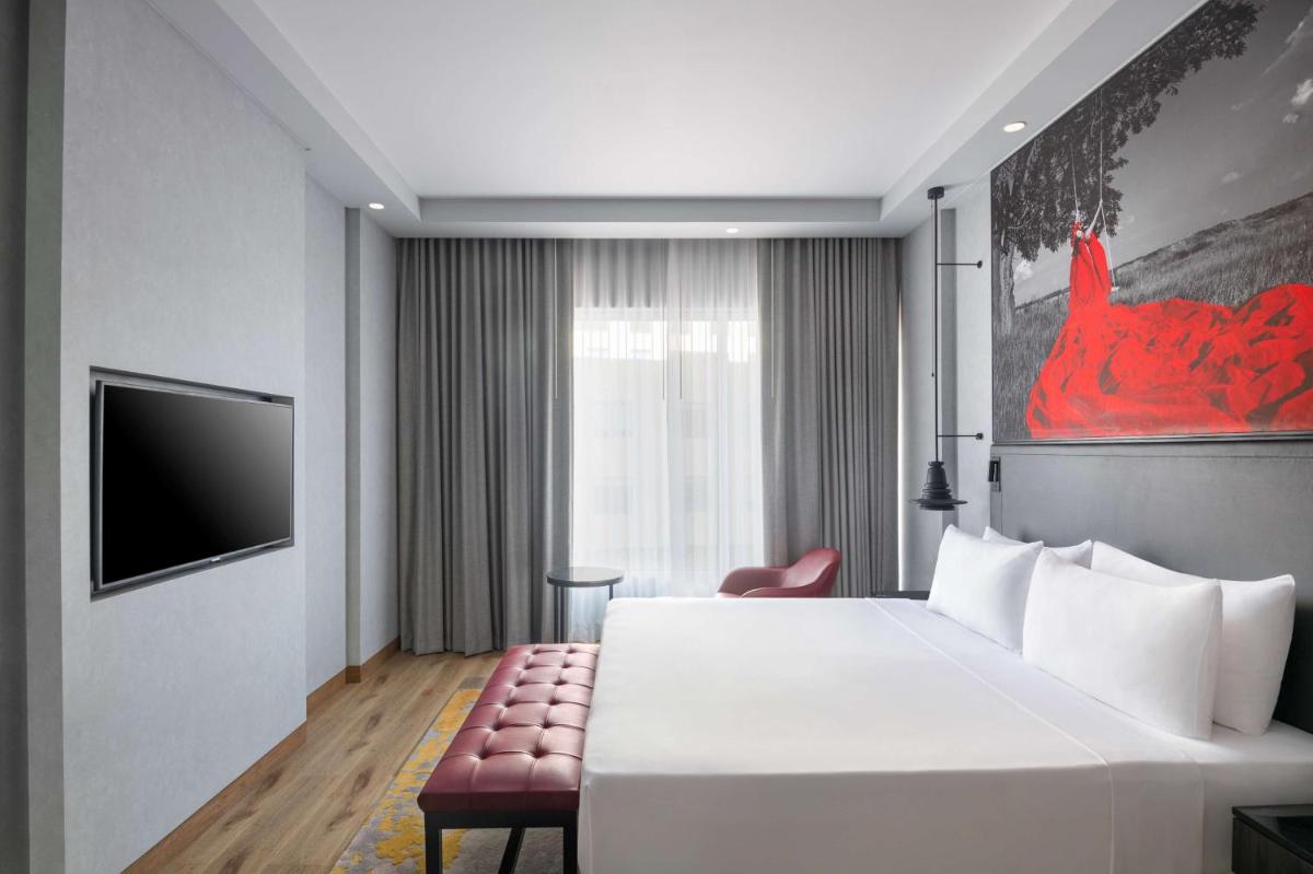 a hotel room with a large white bed and a chair at Radisson RED Chandigarh Mohali in Chandīgarh