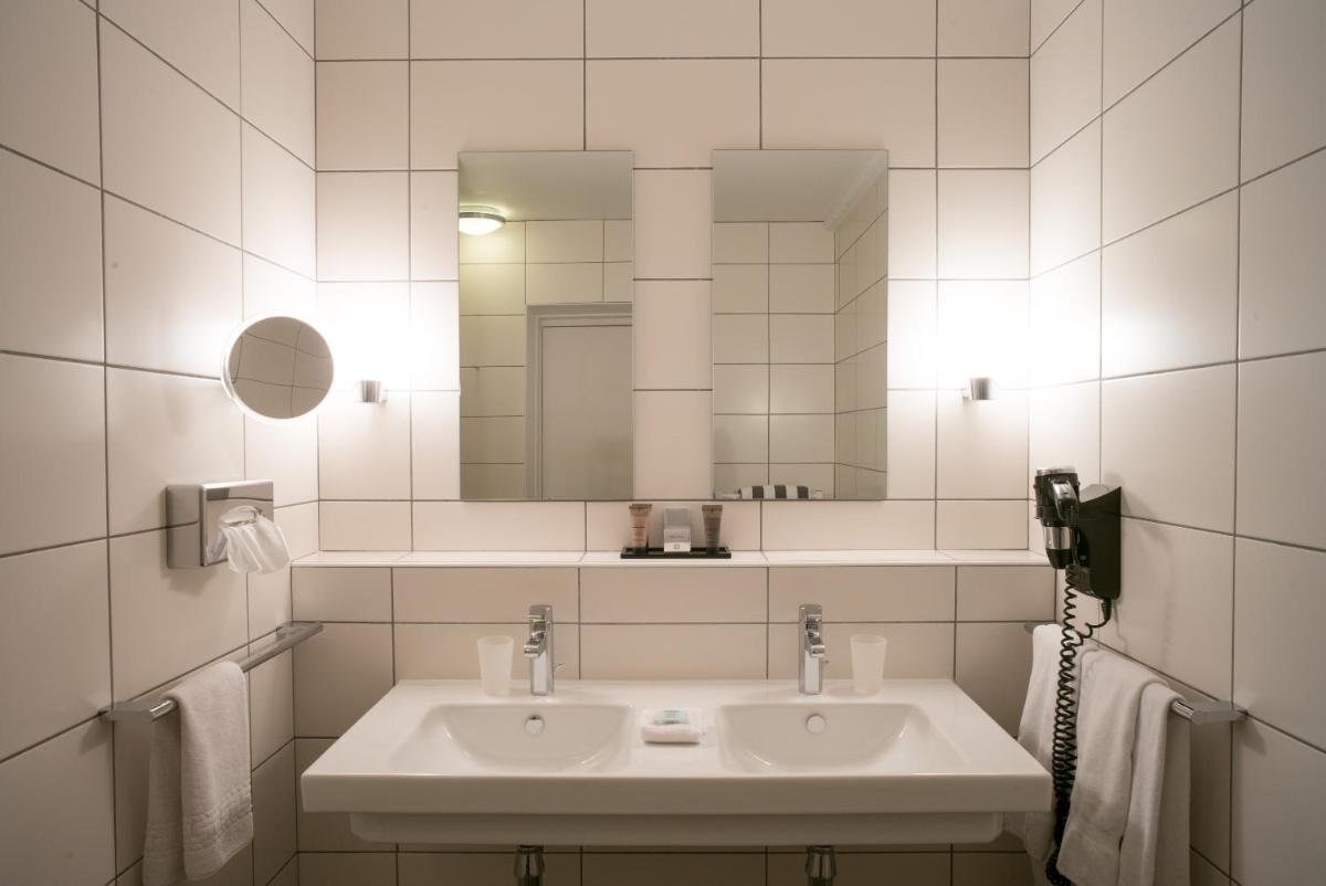 une salle de bains blanche avec un lavabo et un miroir dans l'établissement Hôtel - Spa Les Corderies, à Saint-Valery-sur-Somme