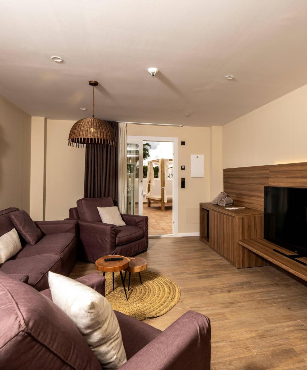 Una sala de estar con sofás y un televisor de pantalla plana. en Eques Petit Resort, en Cala d´Or