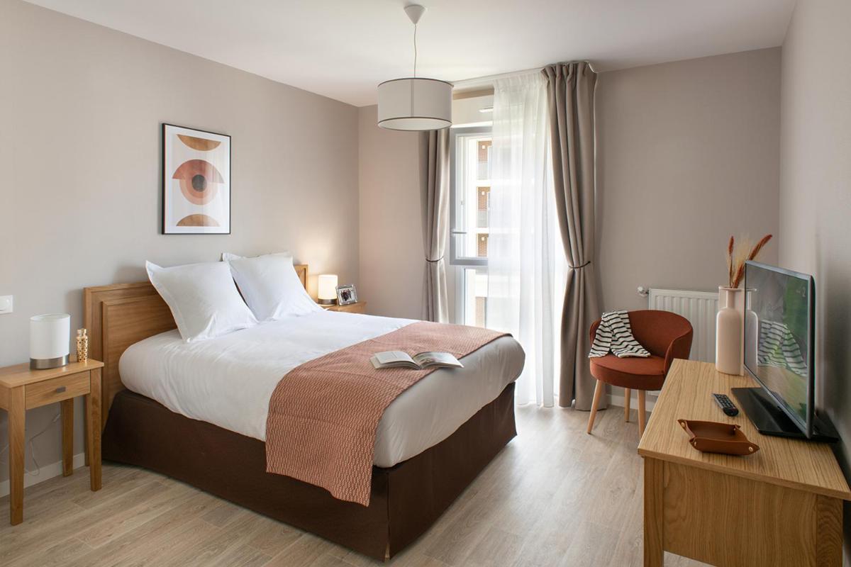 une chambre avec un lit, un bureau et une télévision dans l'établissement Le Critérium, à Écouflant