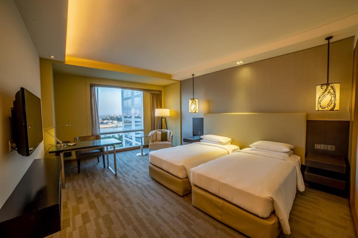 a hotel room with two beds and a desk at Hyatt Regency Ahmedabad in Ahmedabad