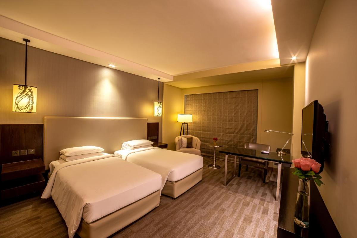 a hotel room with two beds and a desk at Hyatt Regency Ahmedabad in Ahmedabad