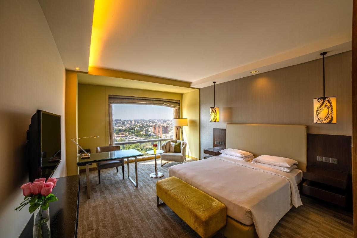 a hotel room with a large bed and a desk at Hyatt Regency Ahmedabad in Ahmedabad