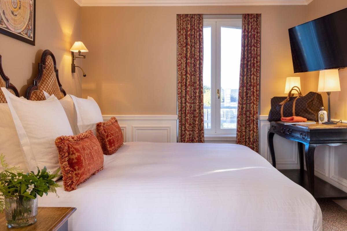 une chambre d'hôtel avec un grand lit et un bureau dans l'établissement Ermitage - Mont-Saint-Michel, à Beauvoir
