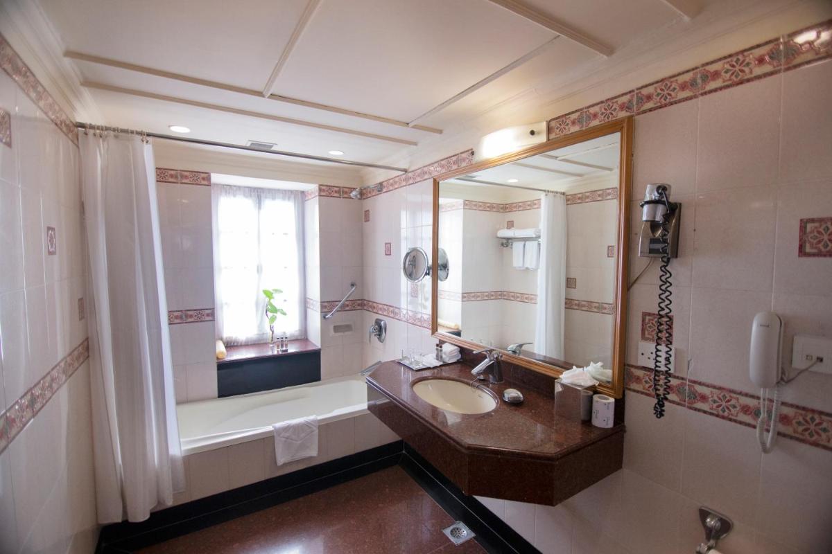a bathroom with a sink and a tub and a mirror at Ambassador, New Delhi - IHCL SeleQtions in New Delhi a bathroom with a sink and a tub and a mirror at Ambassador, New Delhi - IHCL SeleQtions in New Delhi