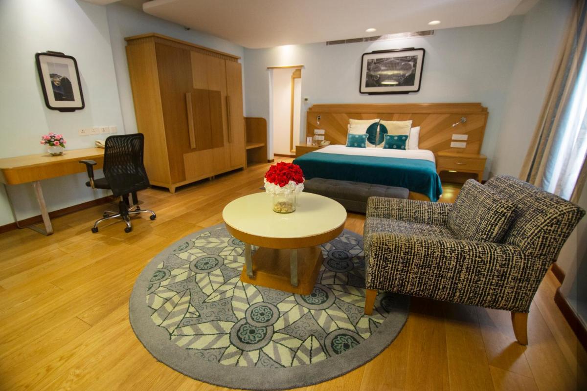 a hotel room with a bed and a table and chairs at Ambassador, New Delhi - IHCL SeleQtions in New Delhi a hotel room with a bed and a table and chairs at Ambassador, New Delhi - IHCL SeleQtions in New Delhi