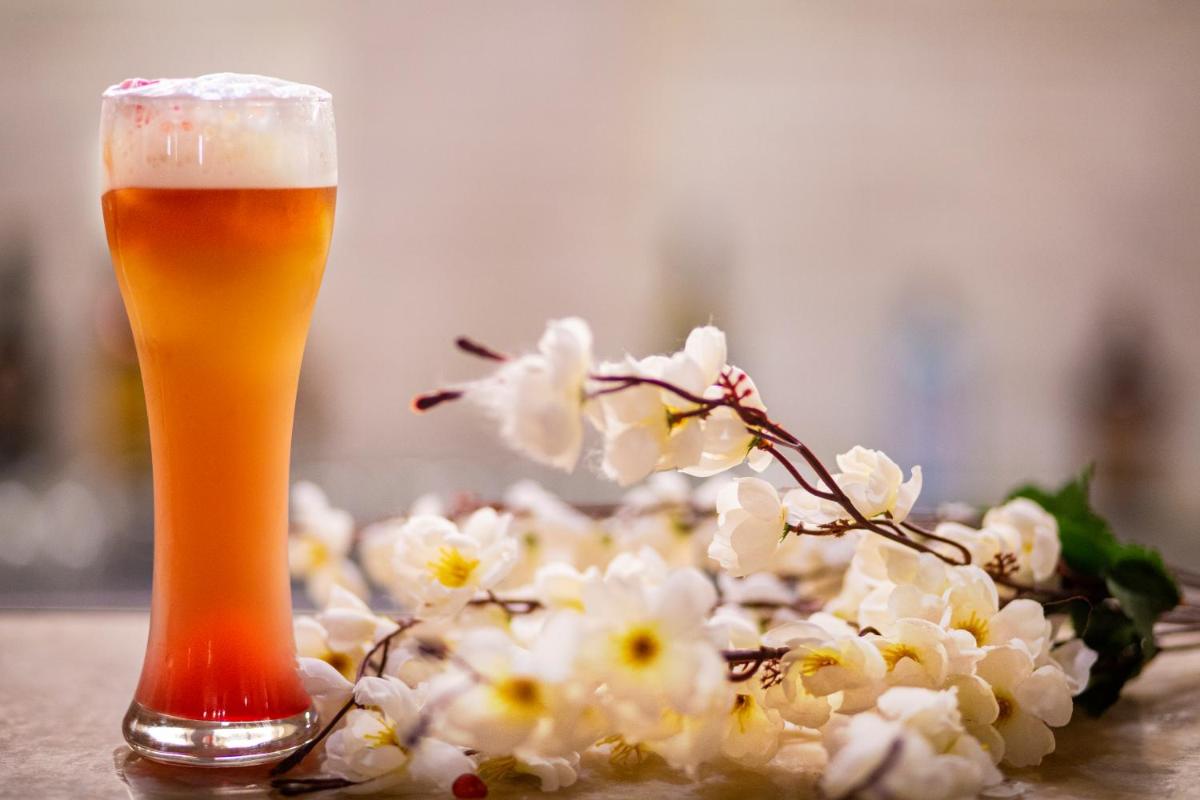 a glass of beer next to a bouquet of flowers at Ambassador, New Delhi - IHCL SeleQtions in New Delhi a glass of beer next to a bouquet of flowers at Ambassador, New Delhi - IHCL SeleQtions in New Delhi