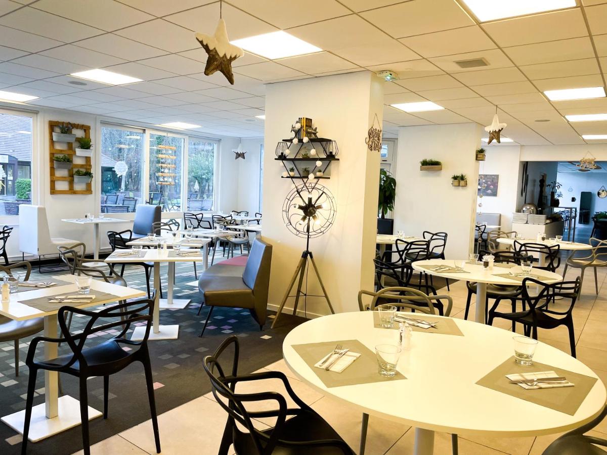 une salle à manger avec des tables et des chaises blanches dans l'établissement Novotel Fontainebleau Ury, à Ury