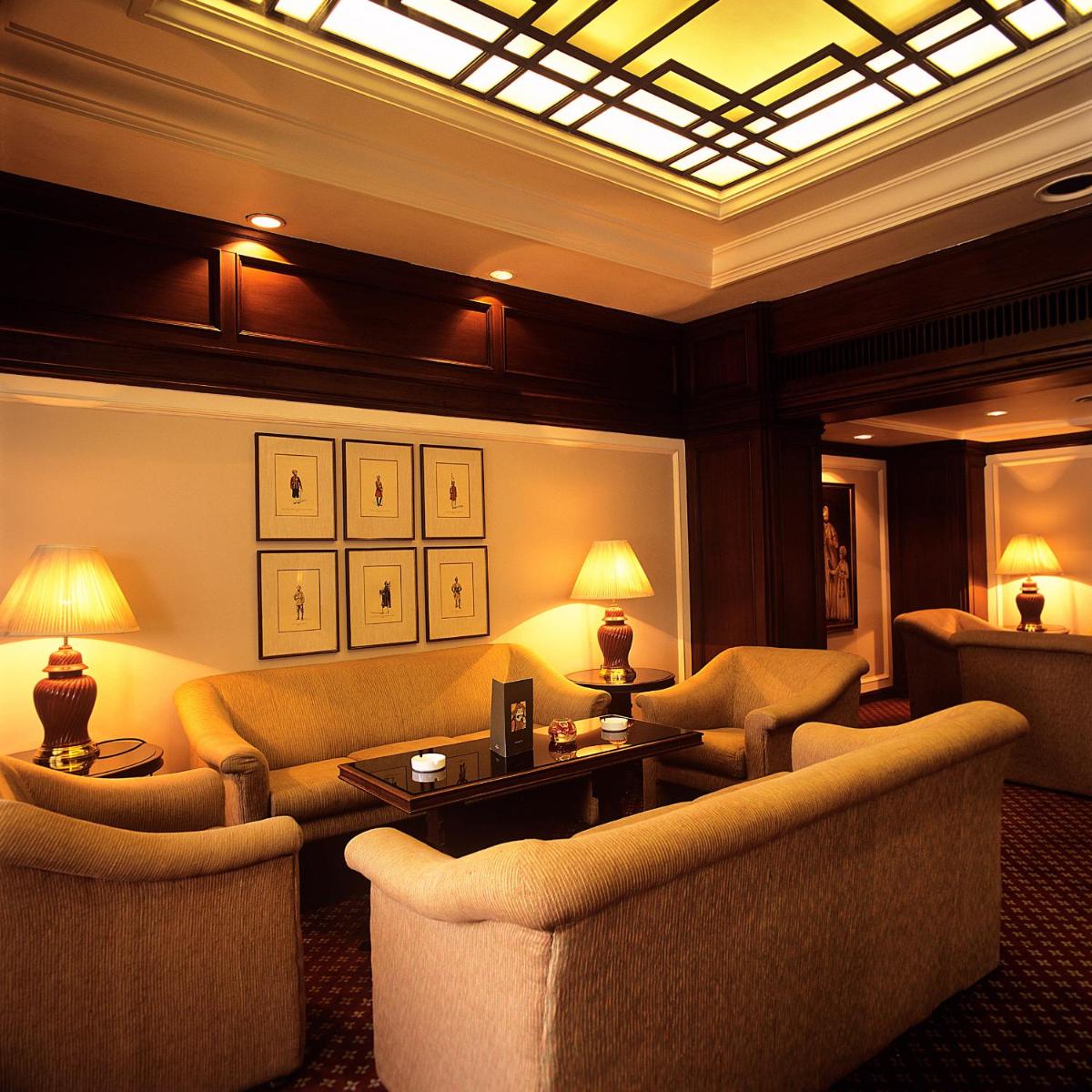 a living room with couches and a table and lamps at Trident Chennai in Chennai