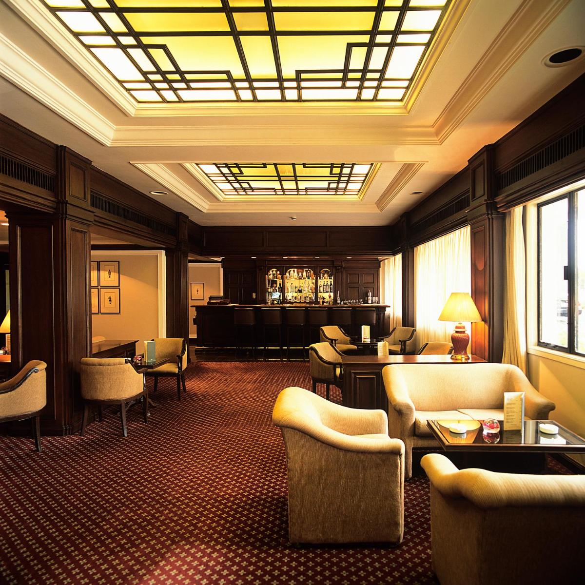 a hotel lobby with chairs and a bar in the background at Trident Chennai in Chennai