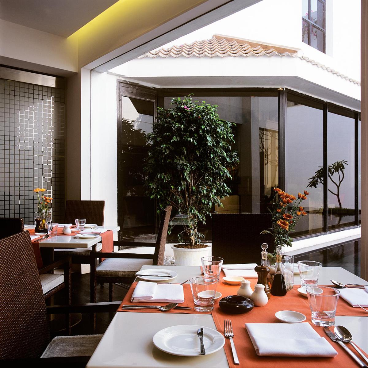 a restaurant with tables and chairs and a large window at Trident Chennai in Chennai