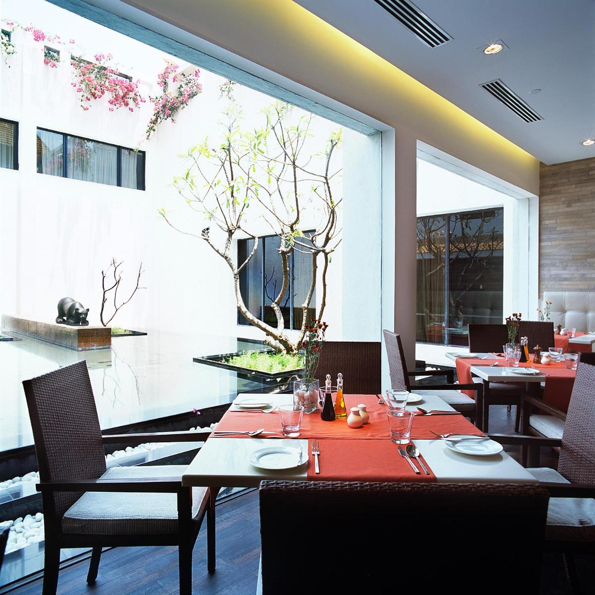 a restaurant with tables and chairs and a large window at Trident Chennai in Chennai