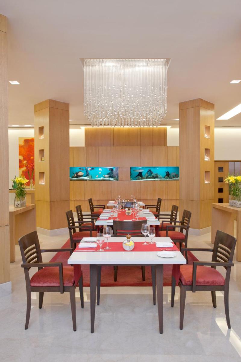 a dining room with a table and chairs and a chandelier at Trident Chennai in Chennai
