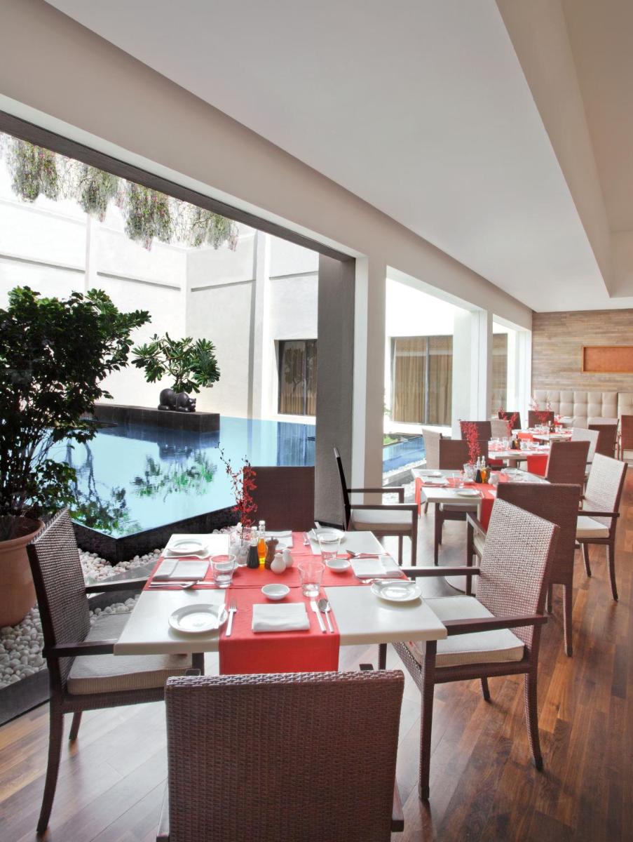 a dining room with tables and chairs and a pool at Trident Chennai in Chennai