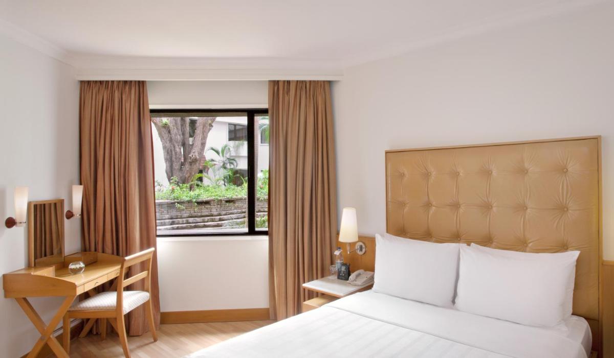 a hotel room with a bed and a desk and a window at Trident Chennai in Chennai