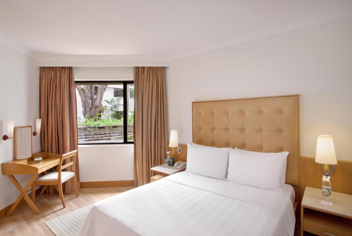 a hotel room with a bed and a desk and a window at Trident Chennai in Chennai