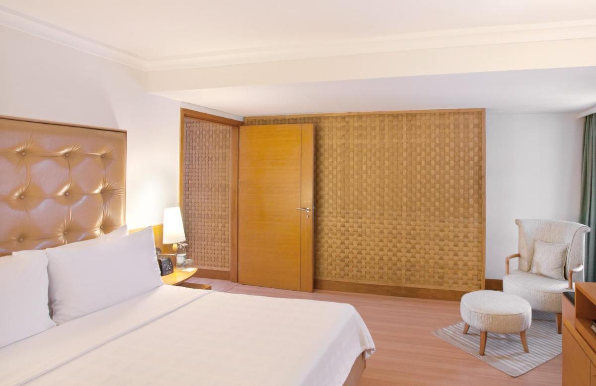 a bedroom with a bed and a chair and a television at Trident Chennai in Chennai