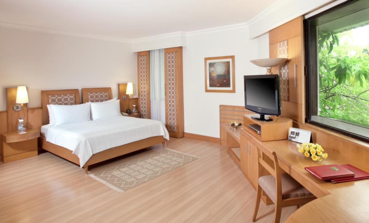 a bedroom with a bed and a desk and a television at Trident Chennai in Chennai