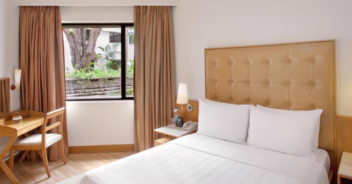 a hotel room with a bed and a desk and a window at Trident Chennai in Chennai