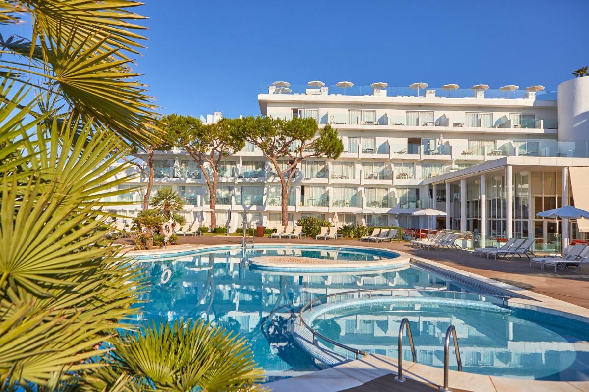 una piscina de hotel con un gran edificio en el fondo en Aparthotel Ponent Mar, en Palmanova