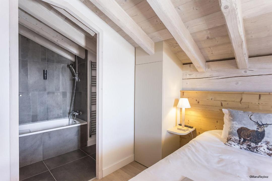 - une chambre avec un lit et une baignoire à côté d'une salle de bains dans l'établissement TERRESENS - Le Hameau de Barthélémy, à La Rosière