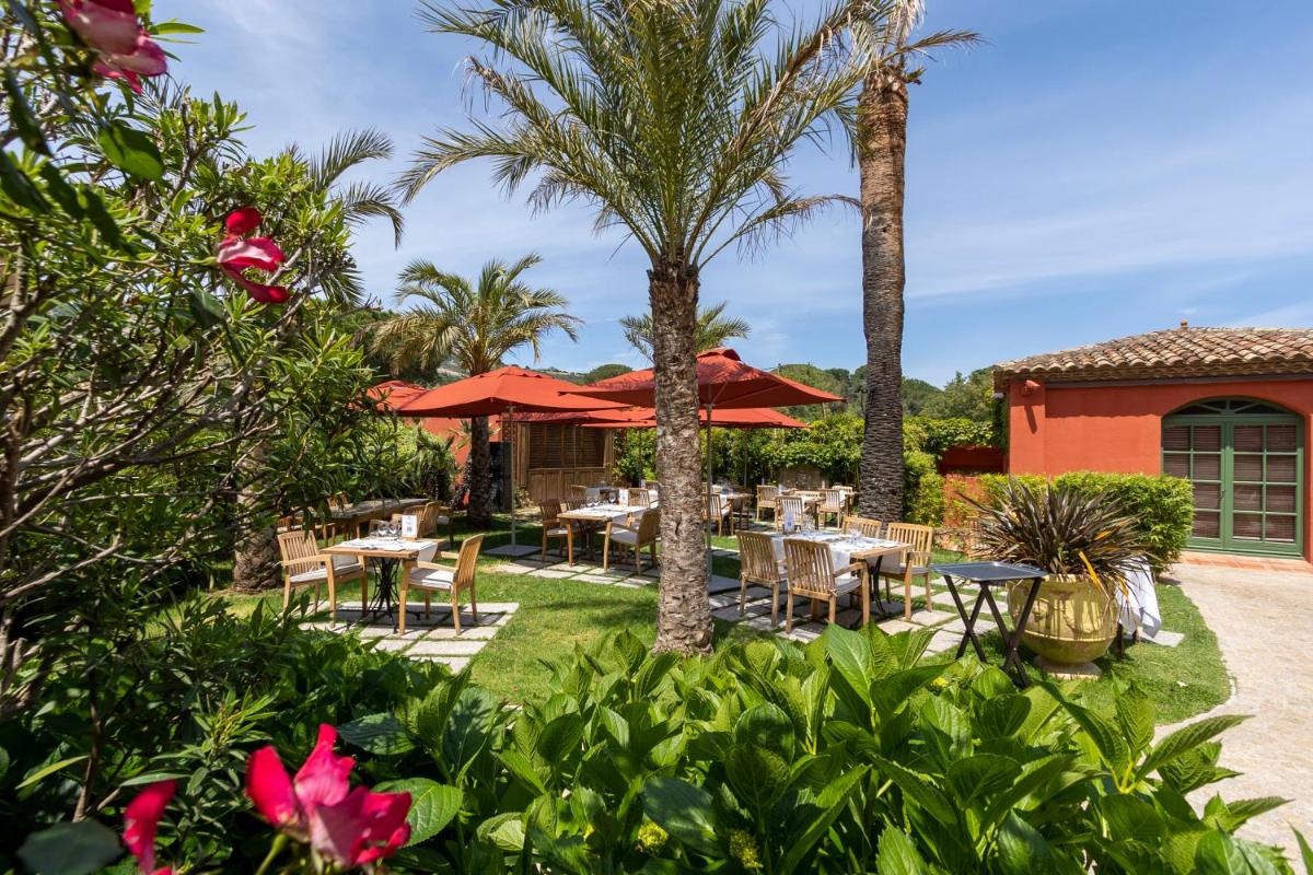 un patio avec tables, chaises et palmiers dans l'établissement La Signoria & Spa, à Calvi