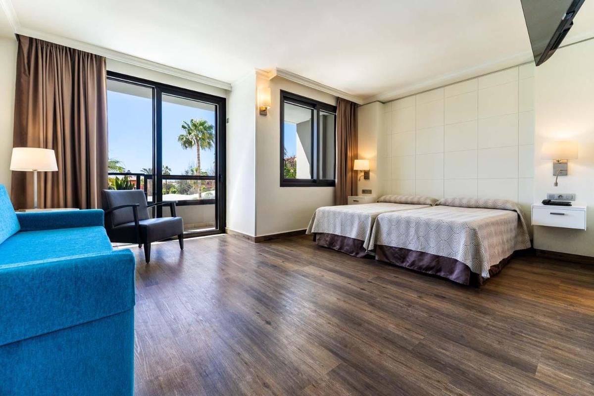Una habitación de hotel con una cama y un sofá azul. en Spring Hotel Bitácora, en Playa de las Américas