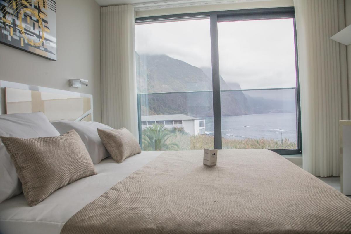 um quarto com uma cama com uma janela grande em Calamar Hotel em São Vicente