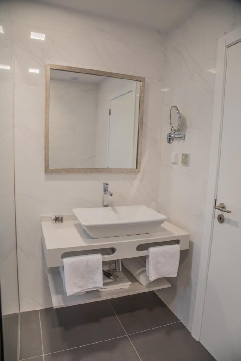 um banheiro branco com uma pia e um espelho em Calamar Hotel em São Vicente