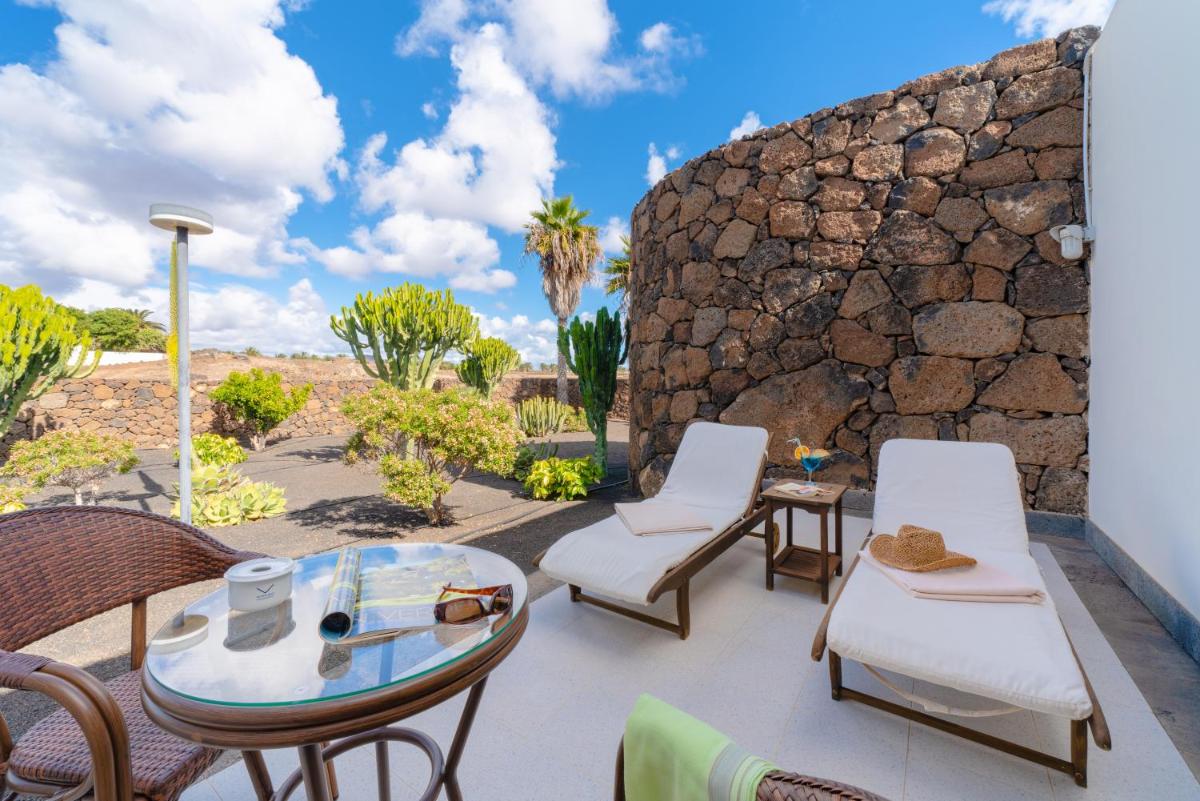 un patio con sillas, mesas y una pared de piedra. en Villa VIK - Hotel Boutique, en Arrecife