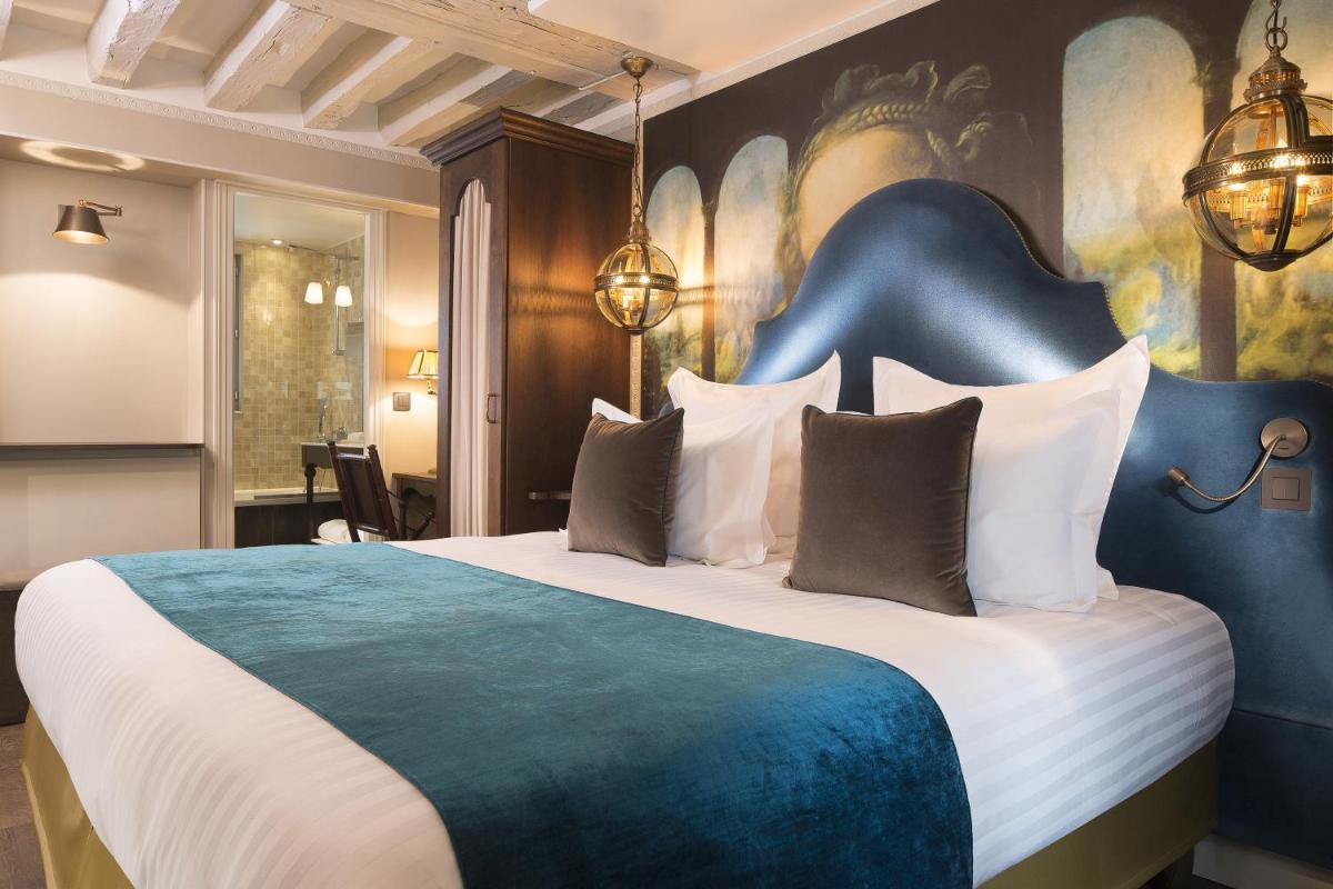 une chambre avec un grand lit avec une tête de lit bleue dans l'établissement Hôtel Da Vinci & Spa, à Paris