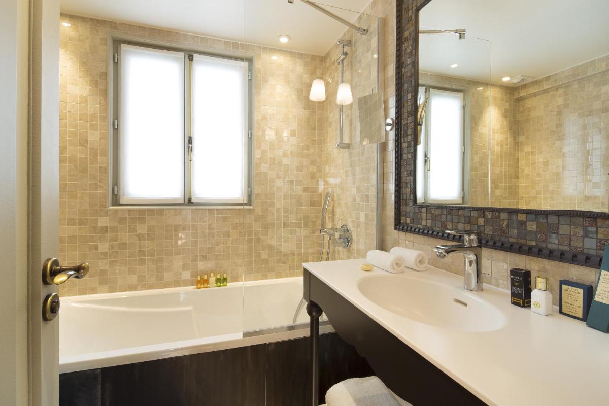 La salle de bains est pourvue d'une baignoire, d'un lavabo, d'une baignoire et d'un miroir. dans l'établissement Hôtel Da Vinci & Spa, à Paris